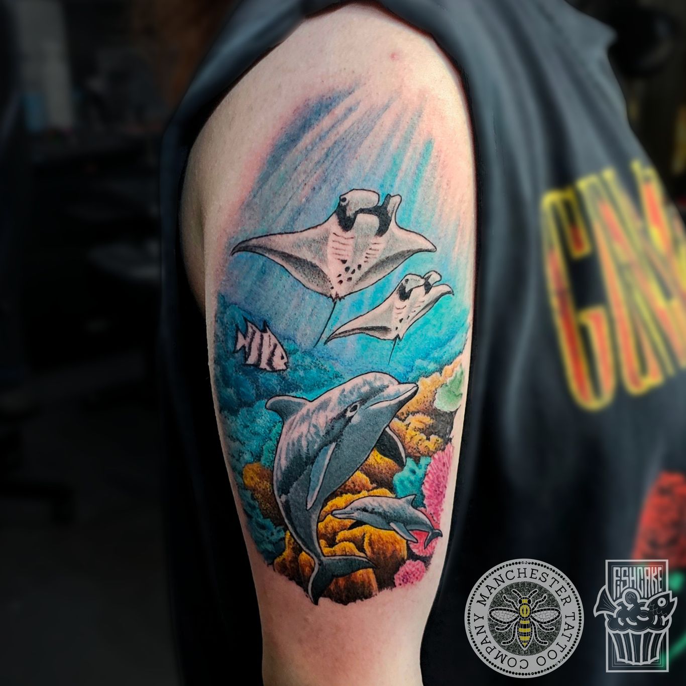 a colour tattoo of a sea life scene including a pair of dolphin  and manta rays